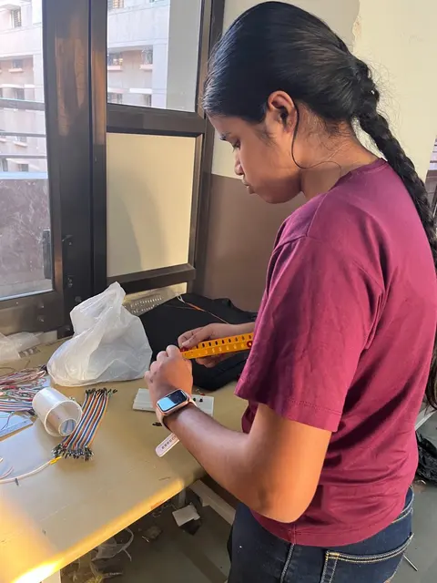 A student at a workbench by a window, working with tools and a plastic bag of parts.