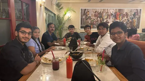 The team and a teacher around a restaurant table.